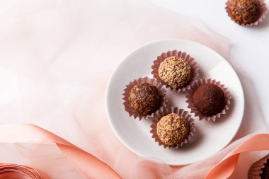 çeşitli çikolatalar ve beyaz arka plan üzerinde şeffaf kumaş ile pembe ipek kurdele ile plaka 