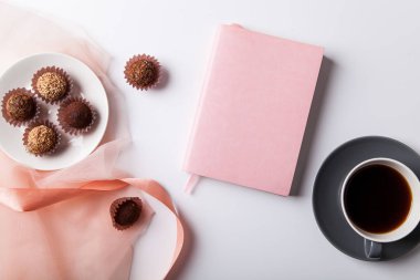 plaka ile çeşitli çikolata truffles ve defter ile beyaz arka planda siyah kahve 