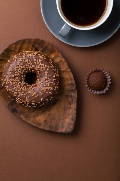 Çikolatalı donuts truffle şeker ve siyah kahve kahverengi arka planda, tek renkli kavramı ile 