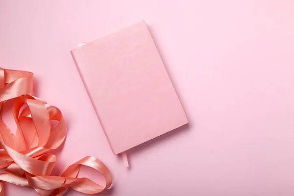 単色の概念 ピンクの背景に光沢のあるピンクのサテンのリボンとピンクのノート — ストック写真