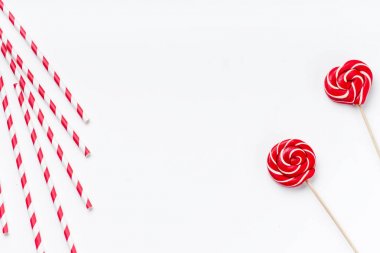Kırmızı ve beyaz parti kamış lolipop ile yuvarlak ve kalp formunda beyaz zemin üzerine izole içme yakın çekim 