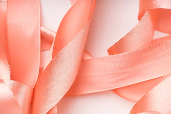 pink silk ribbons curled in spirals on white background