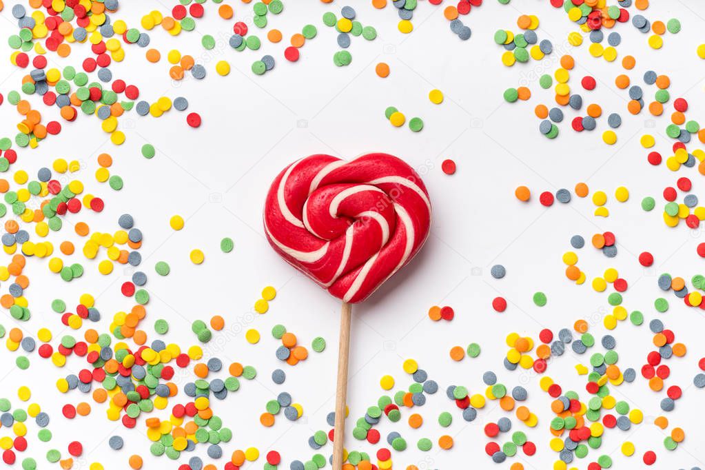 colorful sweet confetti topping with red and white heart-shaped lollipop at center, party concept 