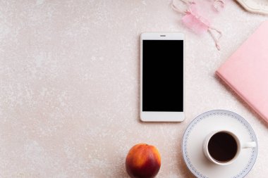 Not defteri ve kahve ile pembe renk arka plan üzerinde telefon ile kadın çalışma alanı 