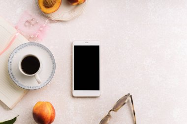 kadın blogger çalışma alanıyla smartphone ve şeftali ve pembe renkli arka plan üzerinde not defteri ile kahve 