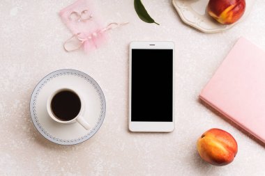 kadın blogger çalışma alanıyla smartphone ve şeftali ve pembe renkli arka plan üzerinde not defteri ile kahve 