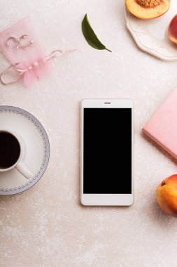 kadın blogger çalışma alanıyla smartphone ve şeftali ve pembe renkli arka plan üzerinde not defteri ile kahve 