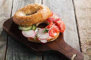 Somon Balık simit ve krem peynir salatalık ve taze turp dilimleri ahşap masa, yakın çekim kesme 