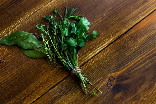 bouquet garni with bay leaves and fresh herbs on dark wooden background