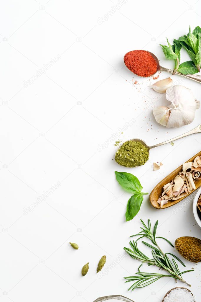 fresh herbs and dried colorful spices in spoons and bowls arranged on side with copy space 