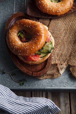 krem peynir ve salatalık dilimleri kesme tahtası üzerinde simit ve somon balıklı metalik tepsi 