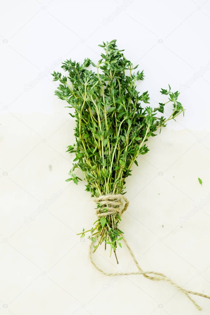 bunch of fresh thyme leaves tied with string on kitchen parchment paper sheet 
