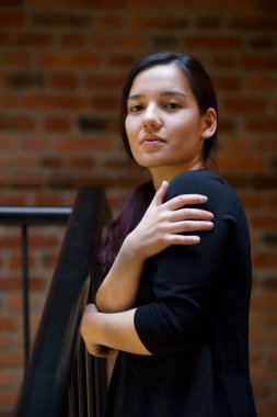 Siyah elbise ayakta kameraya bakarak Bina Tuğla merdiven, karışık ırk genç güzel model kapalı portresi giymiş