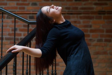 Siyah elbise ayakta tuğla bina merdiven, karışık ırk genç güzel model kapalı portresi giymiş