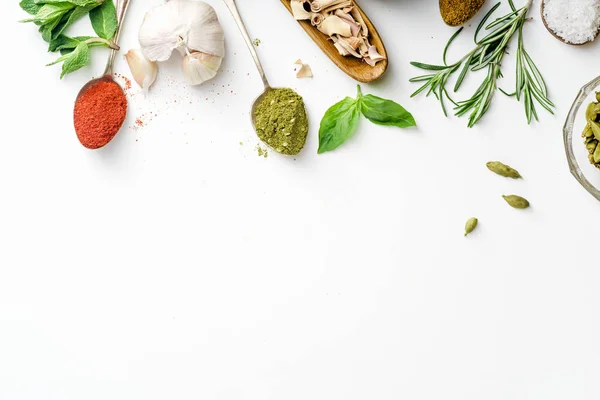 Fresh herbs and dried colorful spices in spoons and bowls arranged with copy space