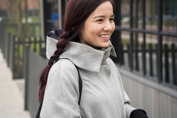 portrait of asian smiling woman with hair arranged in pigtail walking at street in springtime
