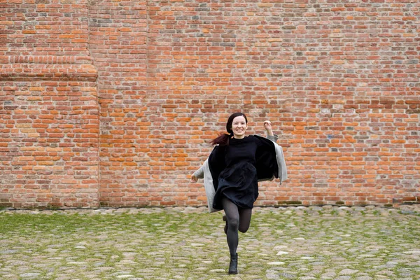 karışık ırk siyah elbise ve tuğla duvar yanında çalışan gri ceket giymiş genç modeli