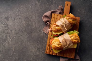 Pastırmalı, peynirli, sebzeli ve ahşap kesim tahtasındaki marullu taze baget sandviçler. 