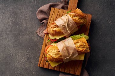 Pastırmalı, peynirli, sebzeli ve ahşap kesim tahtasındaki marullu taze baget sandviçler. 