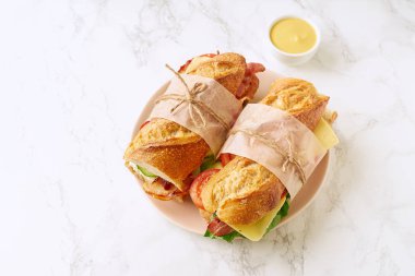 Pastırmalı ve peynirli baget sandviç ve mermer arka planda sebzeli marul.