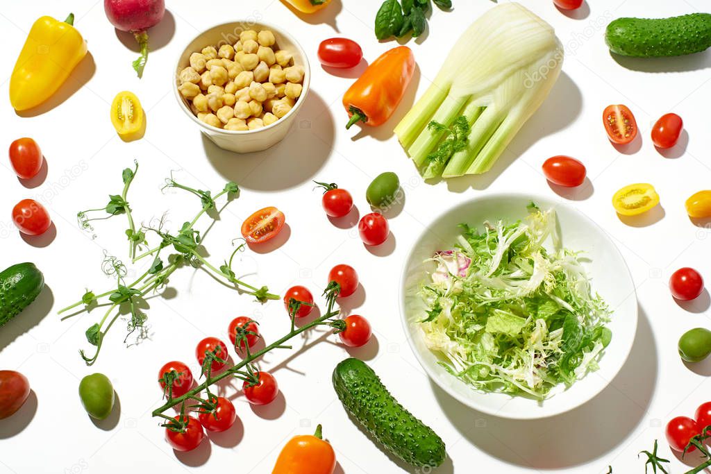 Healthy salad ingredients on white background in hard sunlight with harsh shadows. Vegan meal concept 