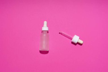 Serum bottle with tube dropper on pink background. Cosmetic flat lay                              
