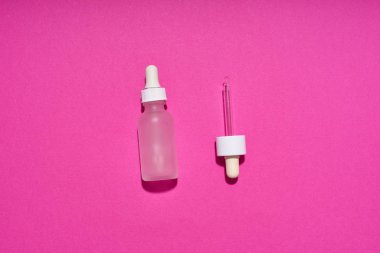 Serum bottle with tube dropper on pink background. Cosmetic flat lay                              