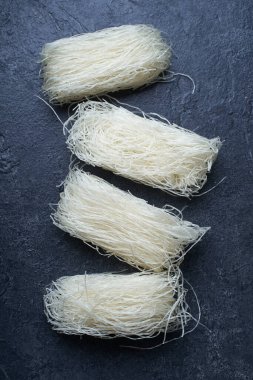  Koyu arkaplanda yuvalarda pişmemiş pirinç erişteleri. Asya mutfağının içeriği                  