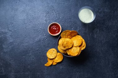  Meksika yuvarlak nacho cipsleri iki kase içinde acı biber sosu ve koyu arka planda bir bardak bira. 