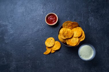  Meksika yuvarlak nacho cipsleri iki kase içinde acı biber sosu ve koyu arka planda bir bardak bira. 