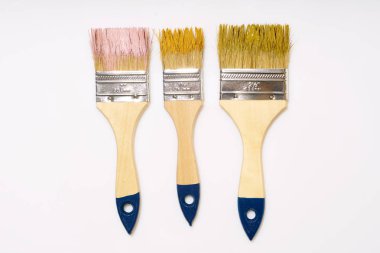 Beyaz arka planda pembe ve yeşil boyalı üç geniş fırça.