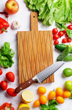 Yeşillikli taze sebze ve salata yaprakları ve mermer yüzeyde aşçı bıçağı ile tahta kesme. Vejetaryen yemek konsepti. Üst görünüm 