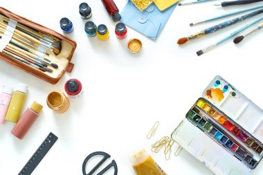 Beyaz arka planda boyaları ve fırçaları olan bağımsız ressamların çalışma yeri, üst görünüm 