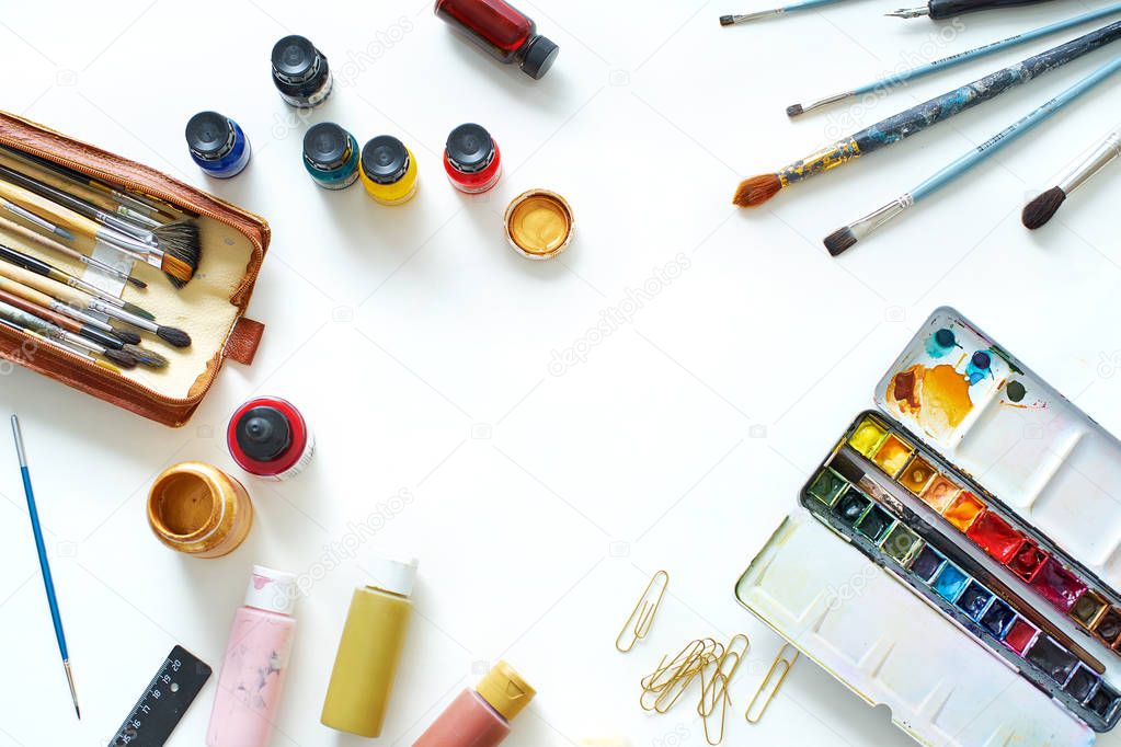 Workplace of freelance artist with paints and brushes on white background, top view 