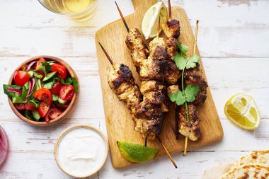 Kırmızı soğanlı tavuk tikka kebabı ve taze salata. Geleneksel Hint yemeği yoğurt ve beyaz ahşap arka planda baharatlarla marine edilmiş tavuktan yapılır..