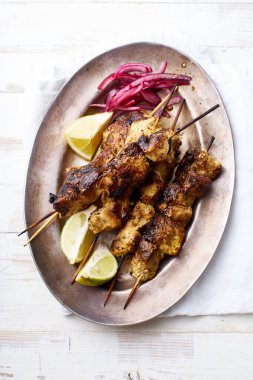 Kırmızı soğan ve limonlu tavuk tikka kebabı. Geleneksel Hint yemeği yoğurt ve beyaz ahşap arka planda baharatlarla marine edilmiş tavuktan yapılır..