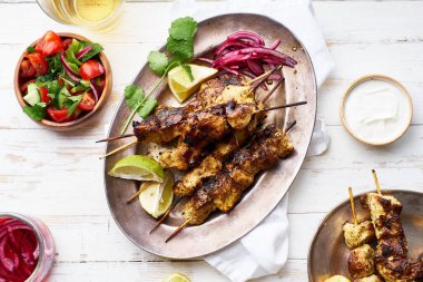 Kırmızı soğanlı tavuk tikka kebabı ve taze salata. Geleneksel Hint yemeği yoğurt ve beyaz ahşap arka planda baharatlarla marine edilmiş tavuktan yapılır..