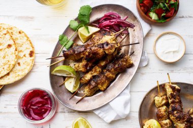 Kırmızı soğanlı tavuk tikka kebabı ve taze salata. Geleneksel Hint yemeği yoğurt ve beyaz ahşap arka planda baharatlarla marine edilmiş tavuktan yapılır..