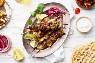 Kırmızı soğanlı tavuk tikka kebabı ve taze salata. Geleneksel Hint yemeği yoğurt ve beyaz ahşap arka planda baharatlarla marine edilmiş tavuktan yapılır..