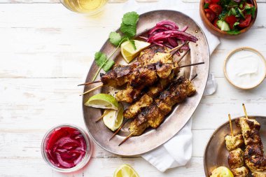 Kırmızı soğanlı tavuk tikka kebabı ve taze salata. Geleneksel Hint yemeği yoğurt ve beyaz ahşap arka planda baharatlarla marine edilmiş tavuktan yapılır..