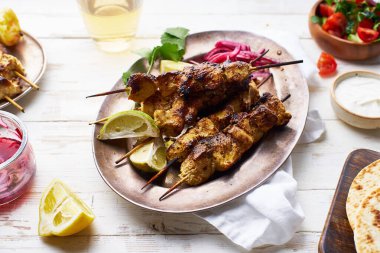 Kırmızı soğanlı tavuk tikka kebabı ve taze salata. Geleneksel Hint yemeği yoğurt ve beyaz ahşap arka planda baharatlarla marine edilmiş tavuktan yapılır..