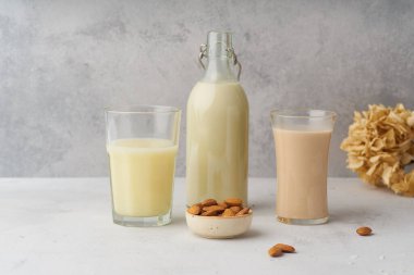 Yulaflı pilav ve bardakta badem sütü ve bej arka planda şişe. Sağlıklı protein vegan içecek konsepti 