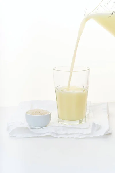 Leche Arroz Vertiendo Vaso Alto Cerca Tazón Con Arroz Sobre —  Fotos de Stock