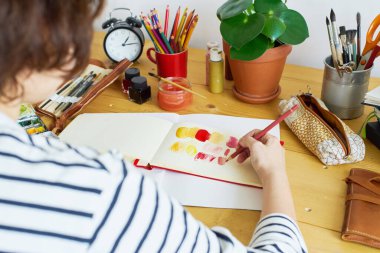 Bir eskiz defterinde ressamın yakın plan resmi. Evden çalışan kadın tasarımcı. Yaratıcı konforlu iş yeri