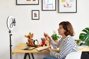 Karantina sırasında çevrimiçi eğitim için resim çeken kadın sanatçı. Evde yüksek lisans yaparak çalışıyorum. Samimi sanatçının stüdyosu. 