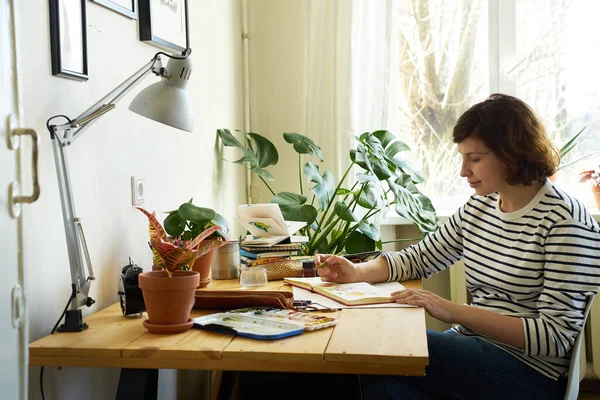 Yerindeki Kadın Sanatçı Evden Çalışıyor Kot Pantolon Çizgili Gömlek Giymiş — Stok fotoğraf