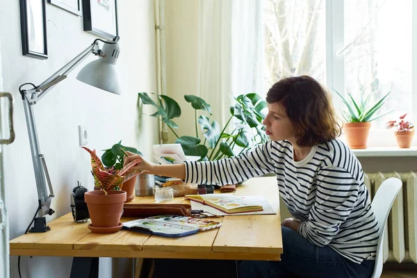 예술가 집에서 일하고 있습니다 청바지와 셔츠를 여자가 테이블에 그림을 그리는 — 스톡 사진