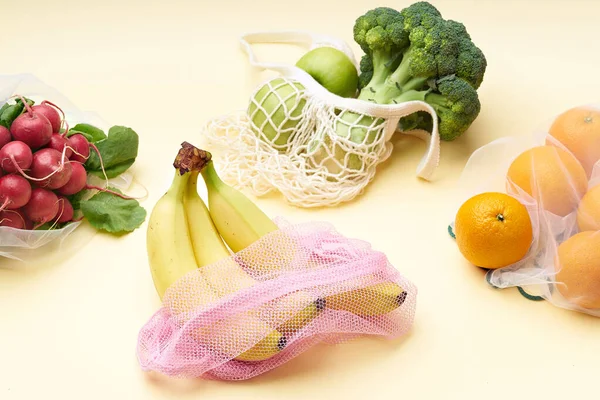 Zero waste food shopping with reusable bags. Flat lay with fruits and vegetables in textile packaging