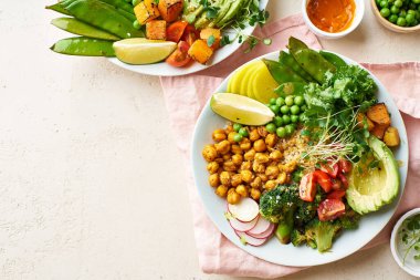 Avokado ve nohutlu sağlıklı vejetaryen yemek kaseleri kinoalı nohut ve mikro yeşillikle süslenmiş sebzeler ve taş zeminde fındık sosu.