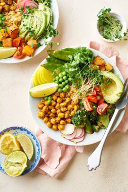 Avokado ve nohutlu sağlıklı vejetaryen yemek kaseleri kinoalı nohut ve mikro yeşillikle süslenmiş sebzeler ve taş zeminde fındık sosu.